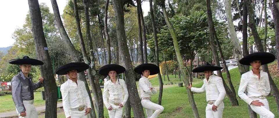 Mariachis económicos en Bogotá: músicos con traje de charro blanco y sombrero en un parque de la ciudad
